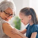 older woman showing child vaccination site on upper arm